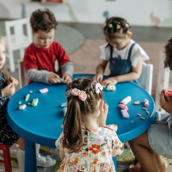 three preschools at a table, playing with clay